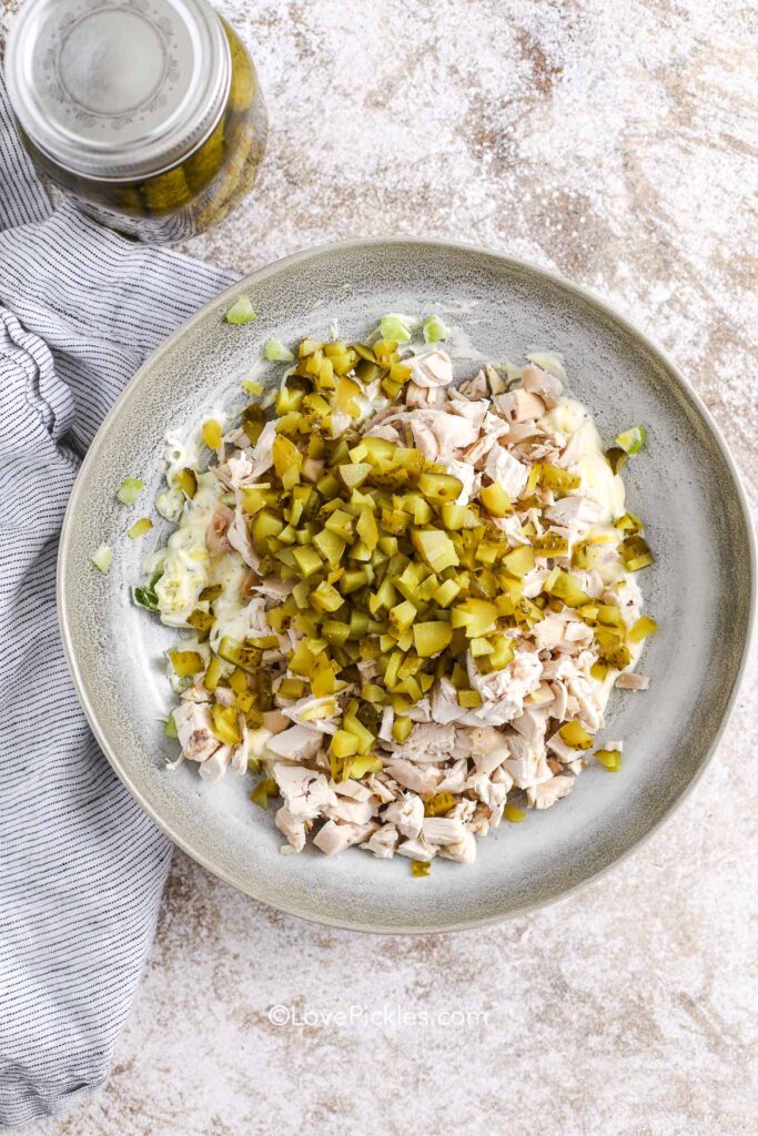 adding chicken and pickles to the dressing for dill pickle chicken salad