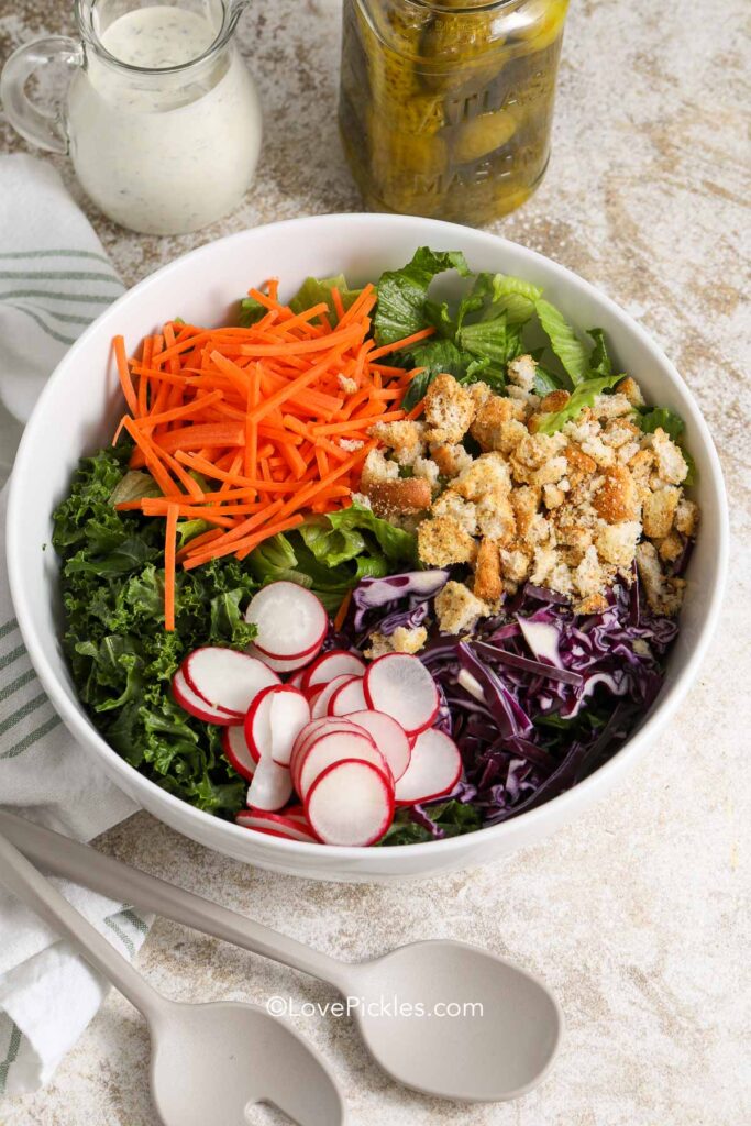 ingredients for dill pickle kale salad in a white bowl