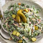 a serving bowl of dill pickle salad with serving spoons