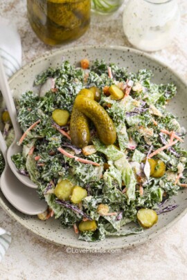 a serving bowl of dill pickle salad with serving spoons