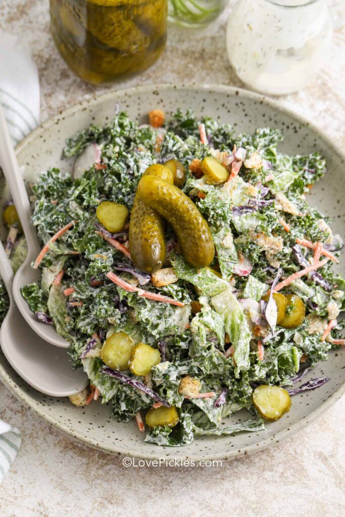 a serving bowl of dill pickle salad with serving spoons
