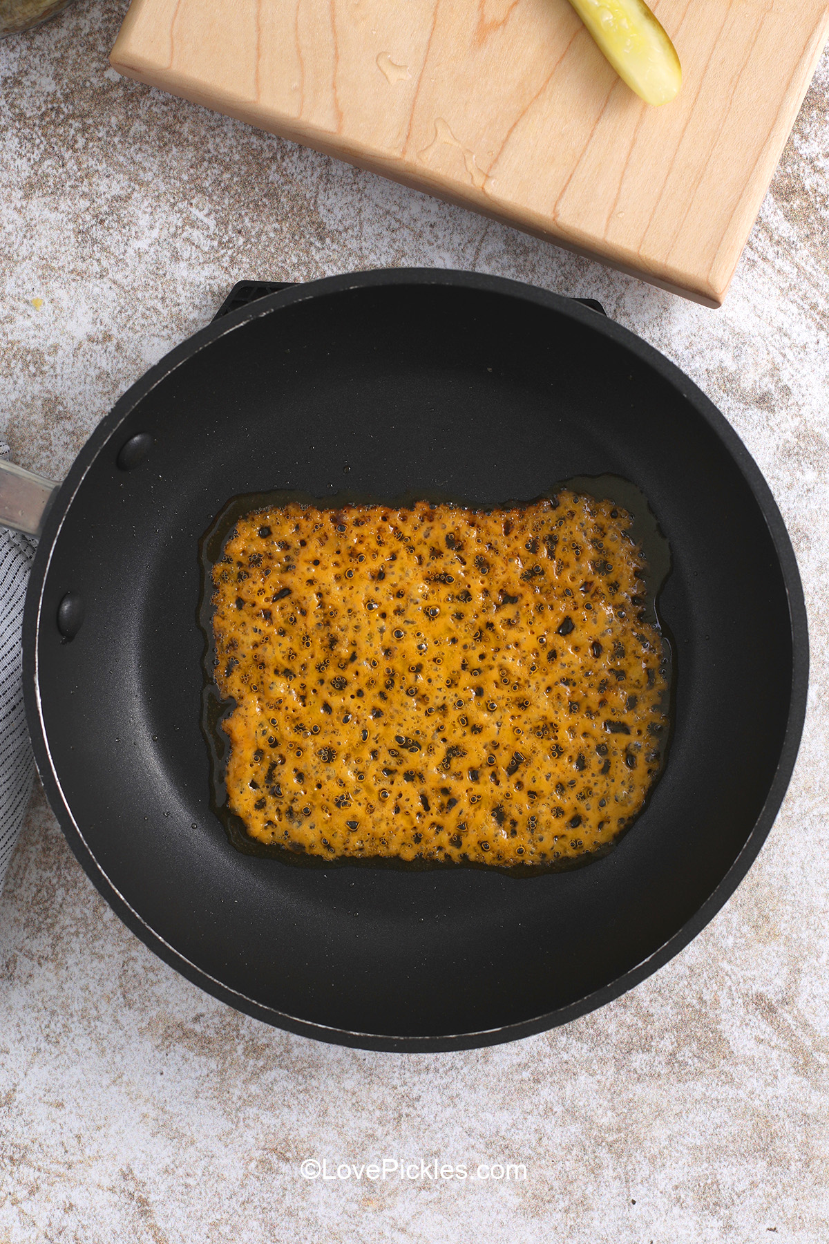 Heating cheese slice in pan until browned and bubbly to make chickles.