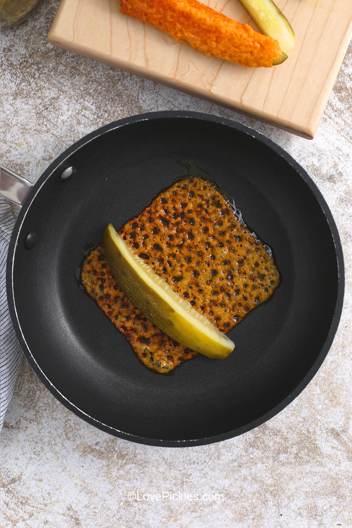 Adding pickle slice to one edge of browned cheese for chickles.