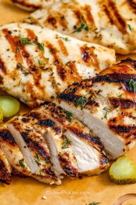 close up of sliced dill pickle marinated chicken breast on a cutting board.