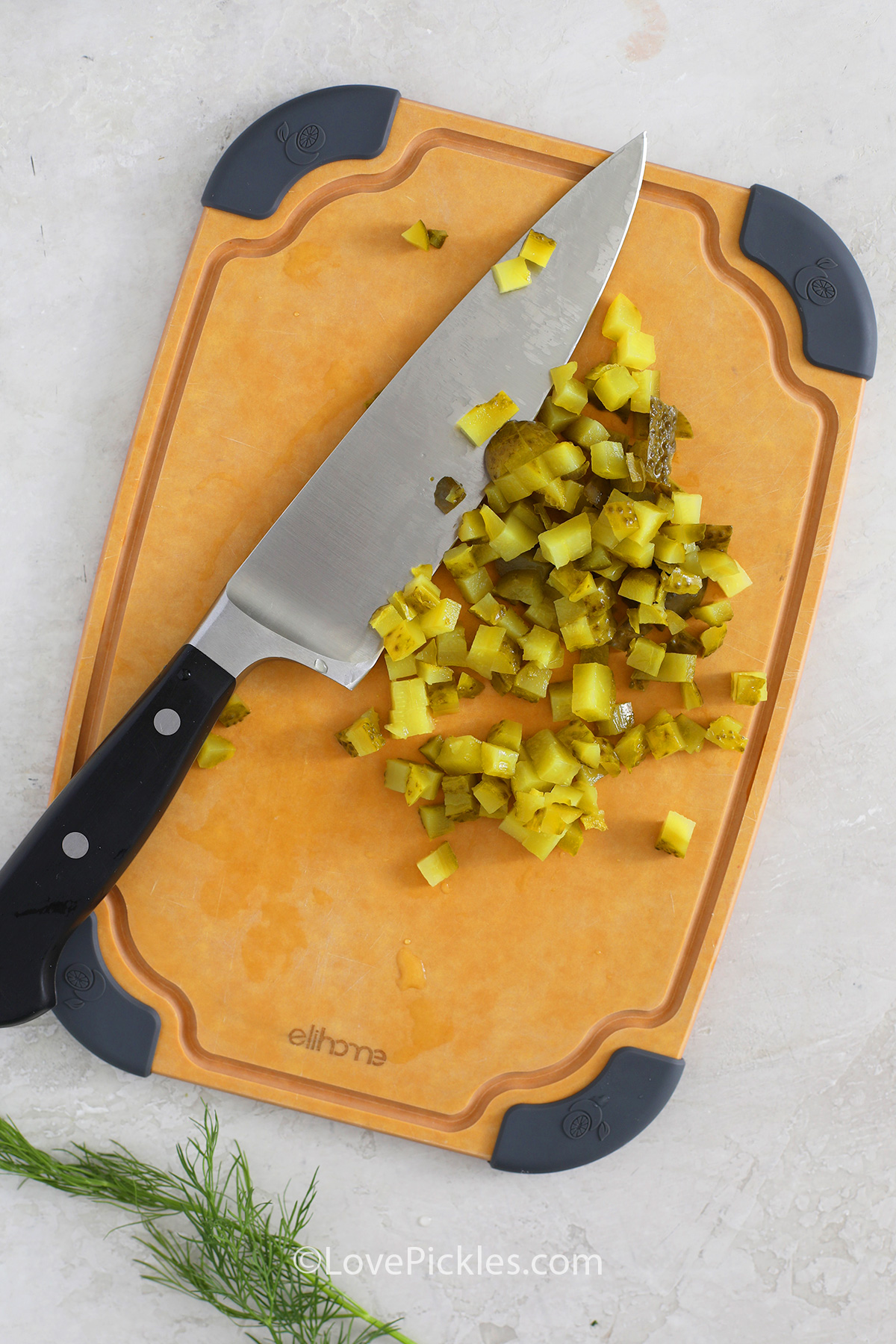 choppe pickles on a cutting board with a knife to make dill pickle dip
