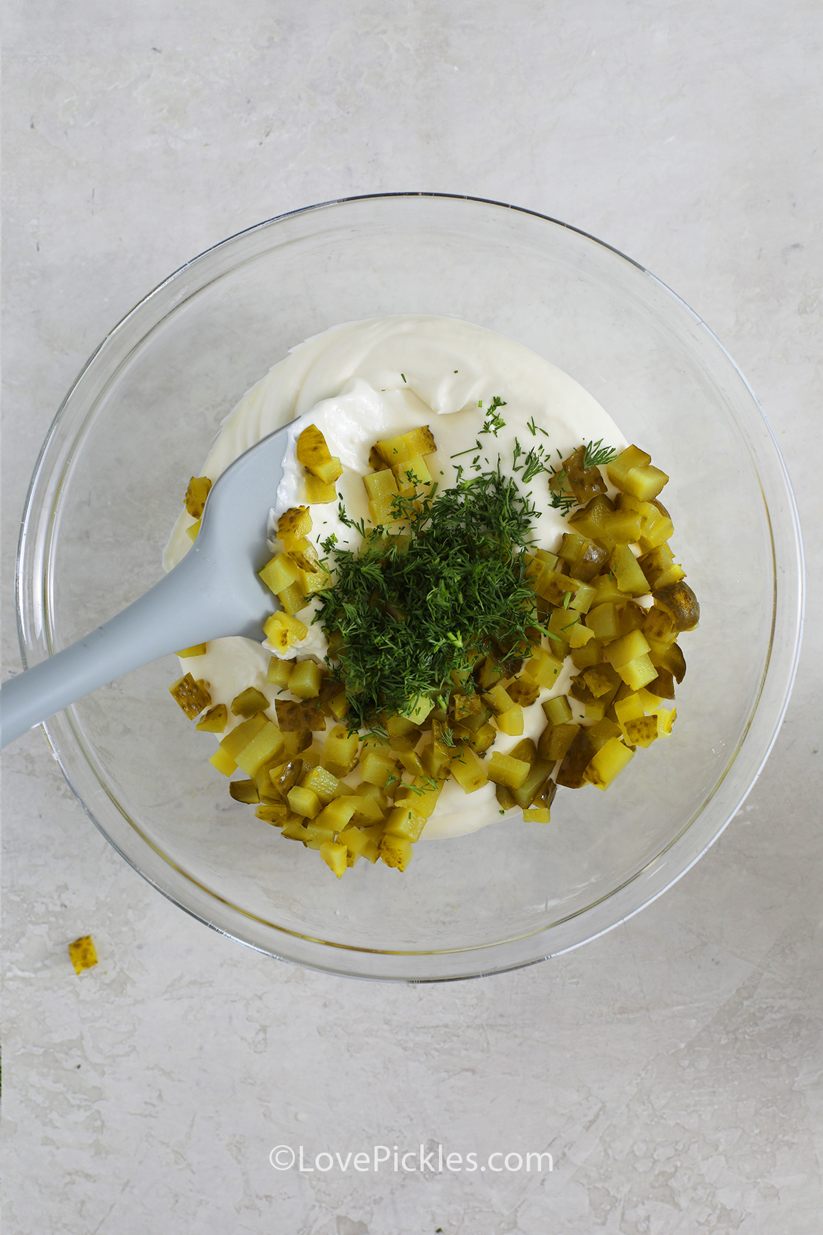 Mixing ingredients in a bowl to make dill pickle dip.