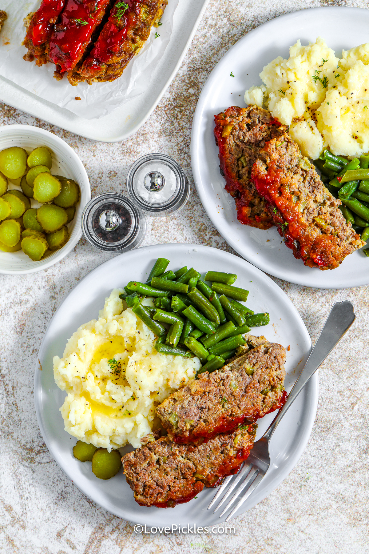plates of dill pickle meatloaf with mashed potatoes and green beans.