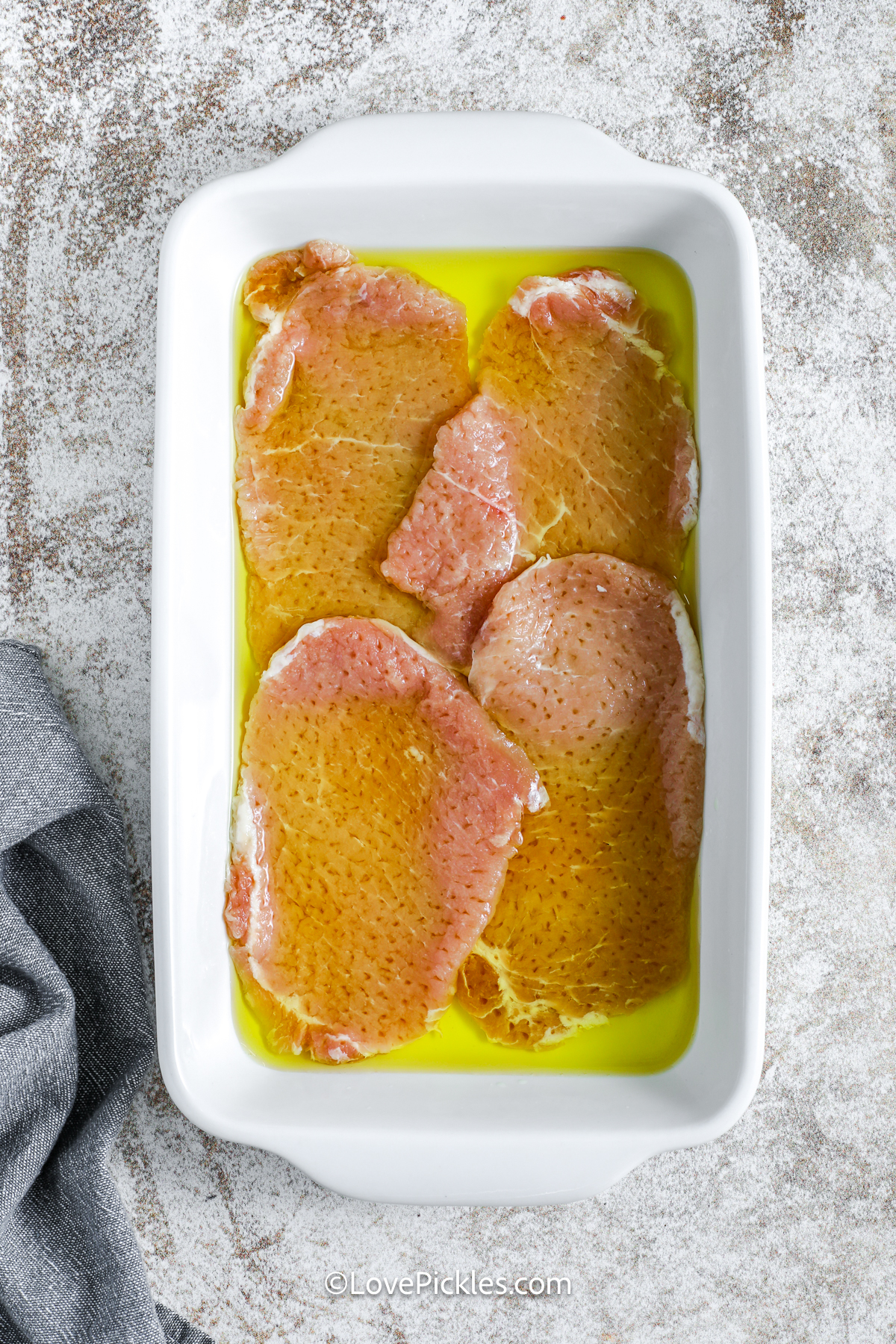 pok chops marinating in a dish for dill pickle schnitzel.