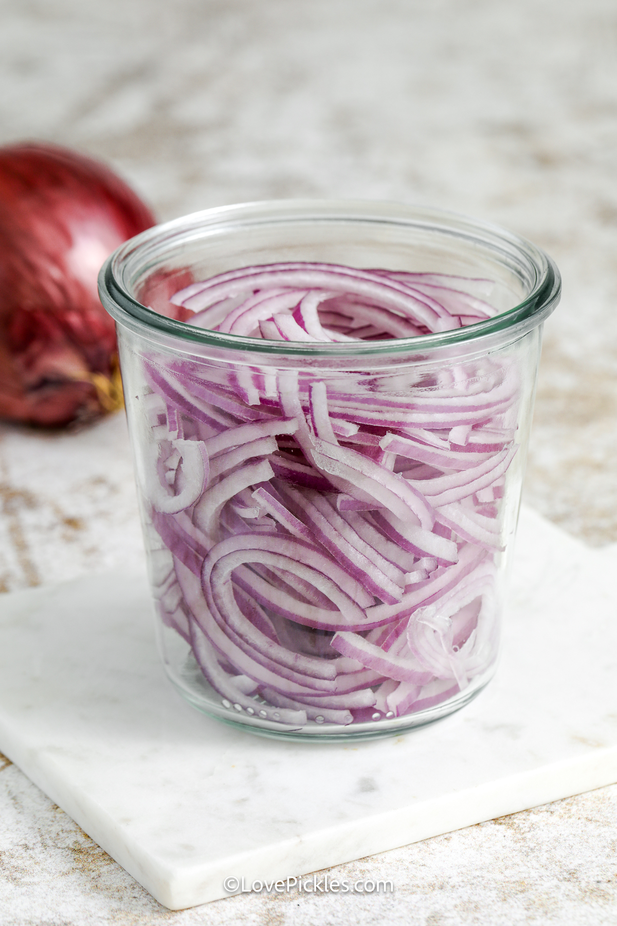 sliced red onions in a jar.