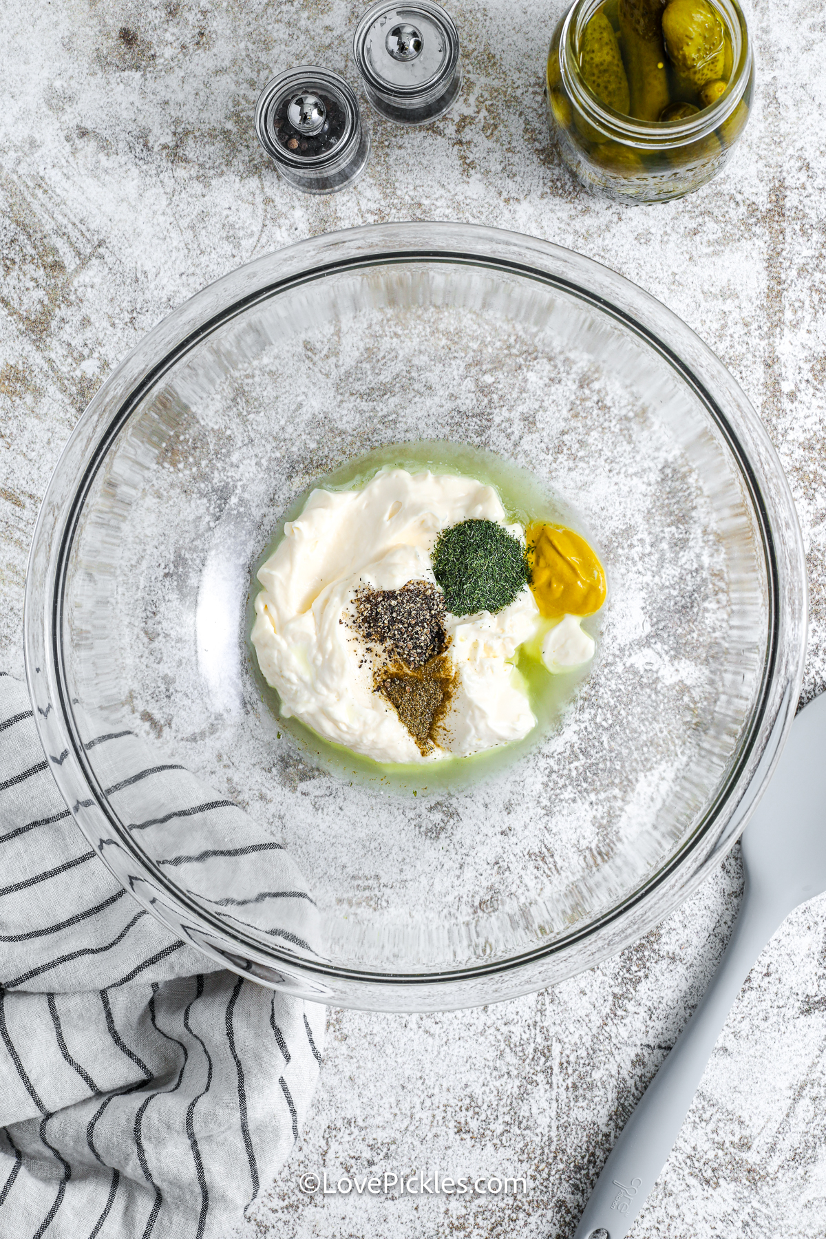 Creamy dill pickle potato salad is loaded with simple ingredients and bold flavor. Yukon gold potatoes give it the perfect bite, and pickle juice adds zing in every forkful. The dressing blends mayo, mustard, and dill for a classic tangy finish, while celery and egg add crunch and richness. Prep it ahead—it’s even better the next day and perfect for picnics or potlucks. #lovepickles ingredients for dill pickle potato salad in a bowl