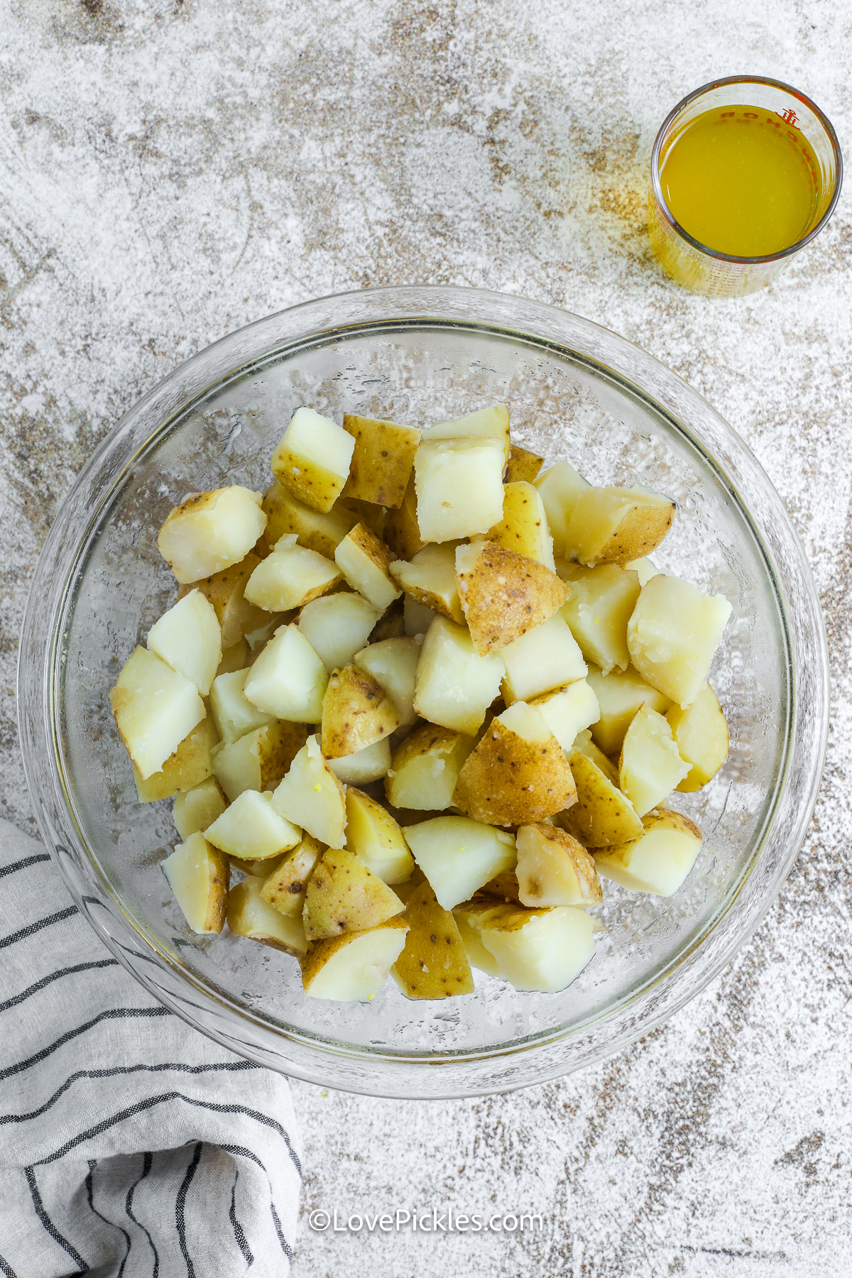 This dill pickle potato salad has everything you want in a classic side—creamy, tangy, and full of fresh crunch. Yukon gold potatoes soak up flavorful pickle juice before being tossed with egg, celery, pickles, and a simple mayo-based dressing. It’s easy to make and even better after chilling in the fridge. Bring this to your next cookout and watch it disappear! #lovepickles cooked potatoes in a bowl for dill pickle potato salad.