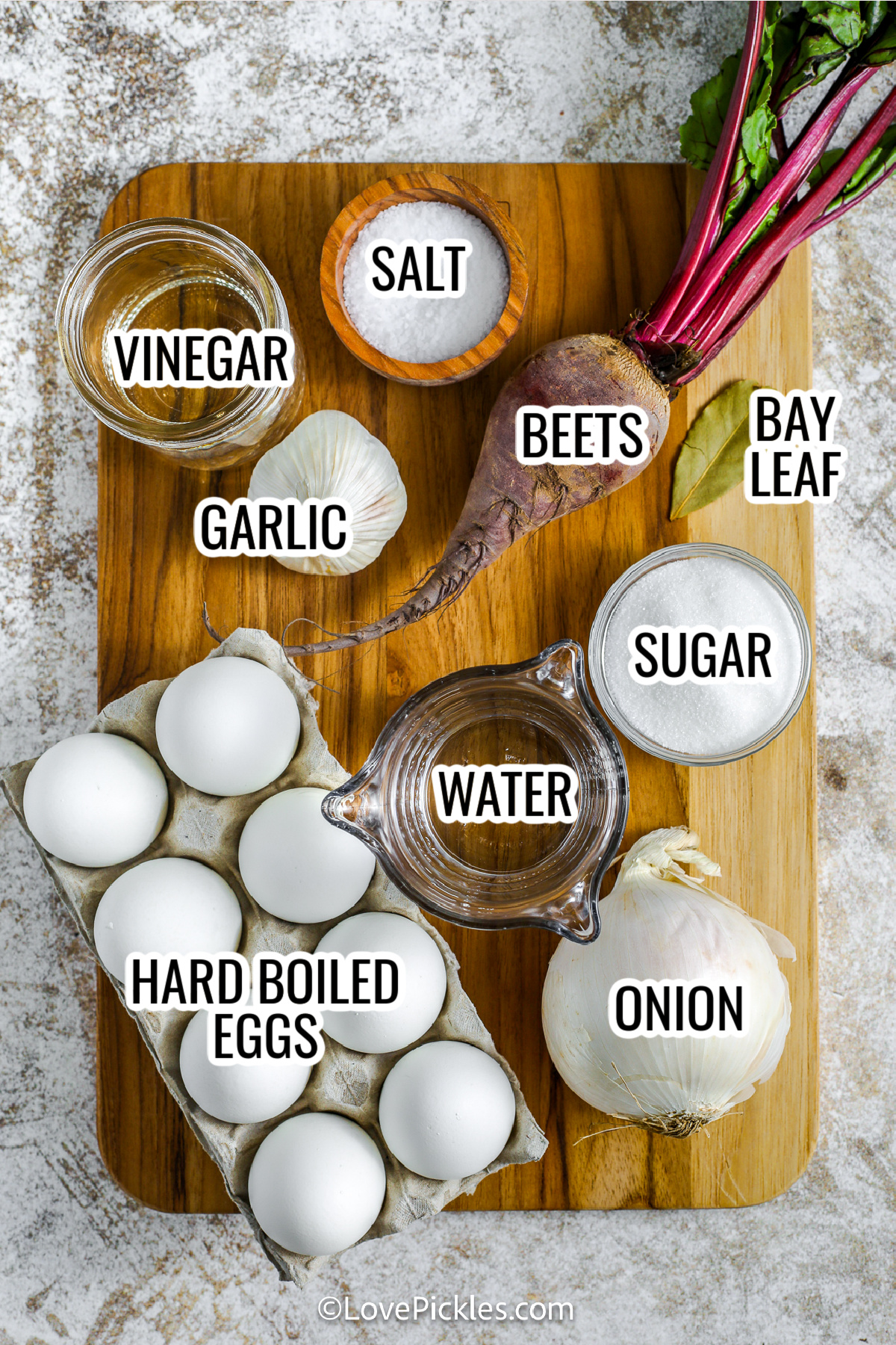 ingredients for beet pickled eggs, including vinegar, garlic, salt, beets, bay leaf, garlic, sugar, water, hard-boiled eggs, and onion