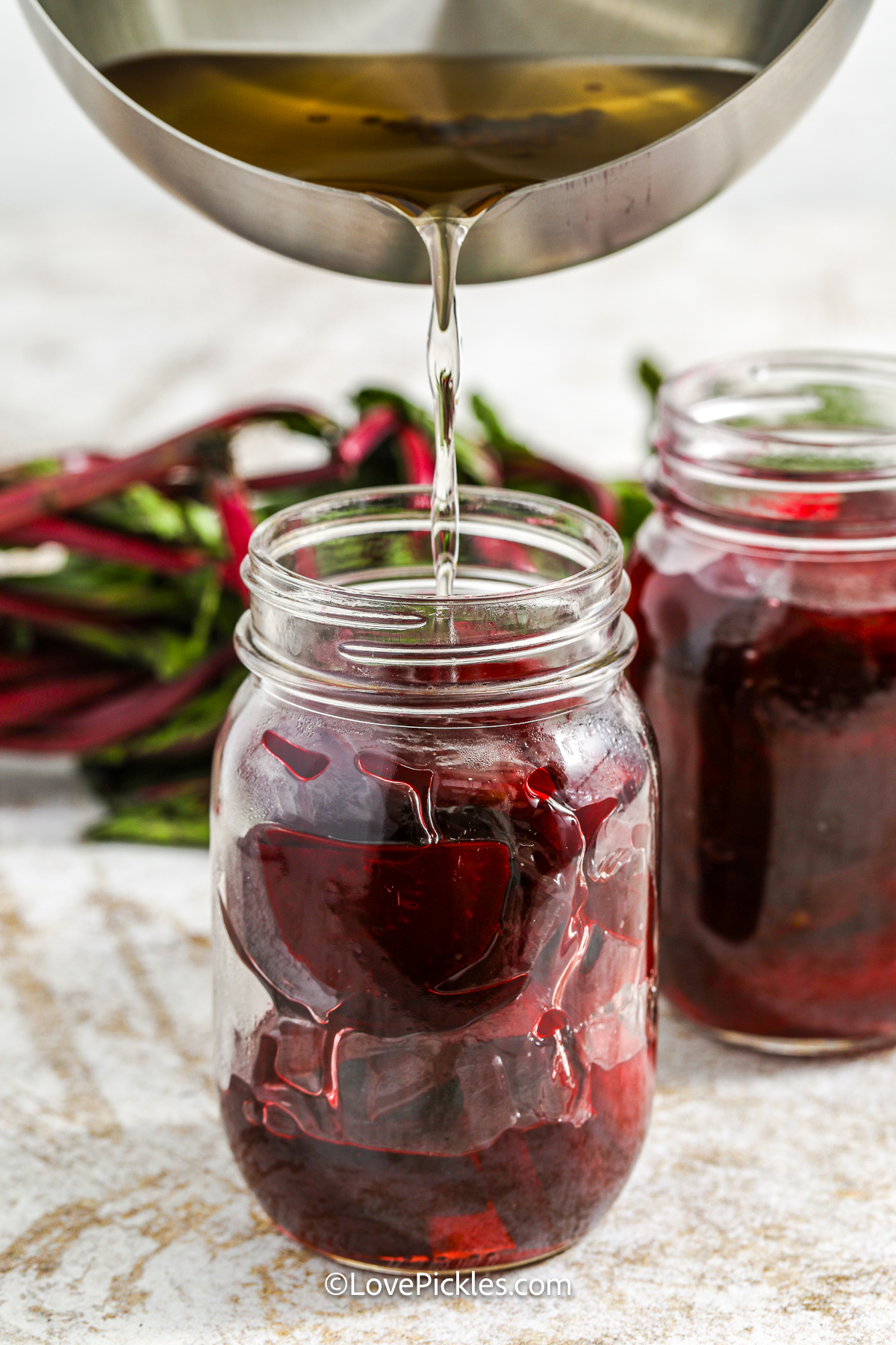 pouring liquid into a jar with beets to make quick pickled beets