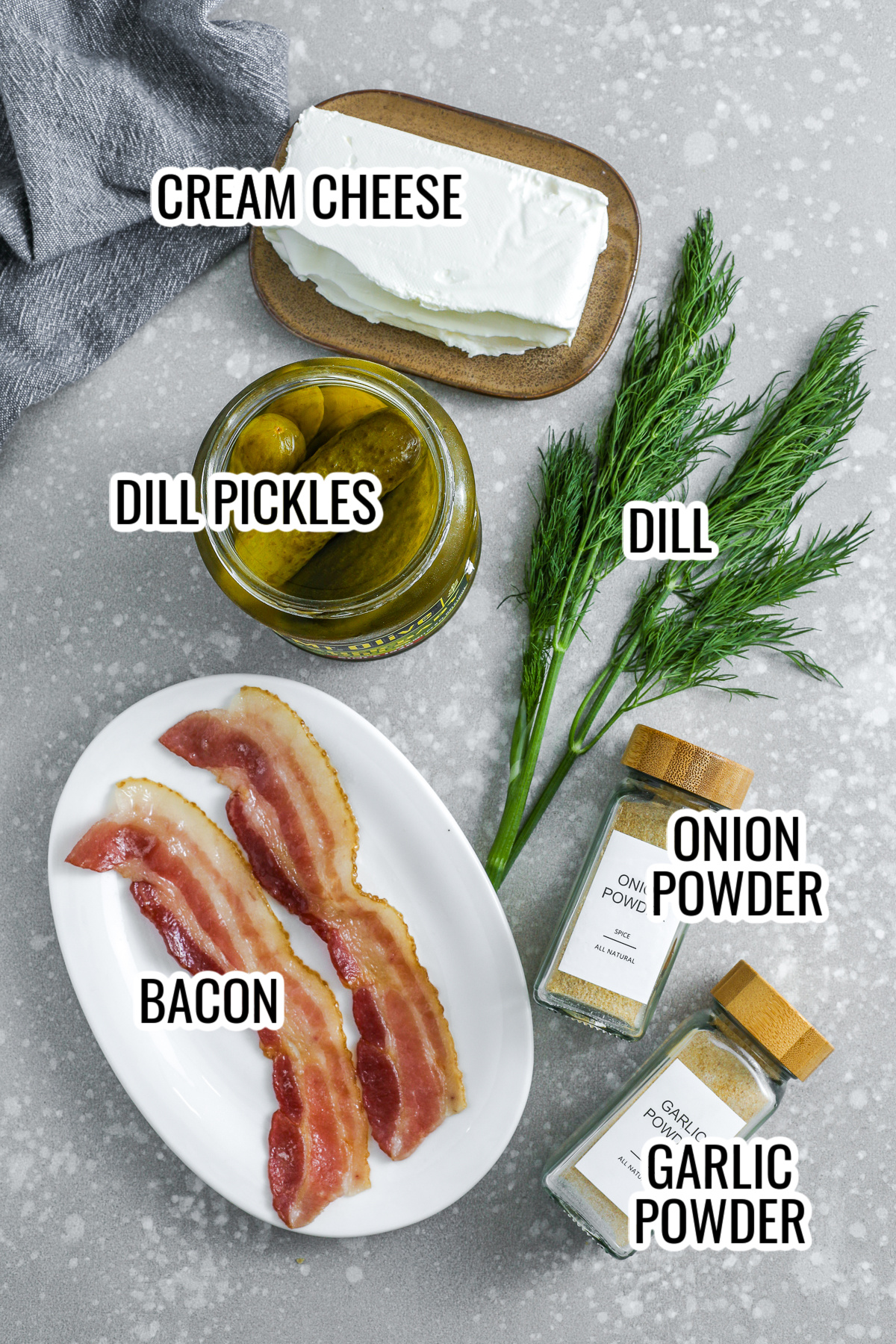 ingredients assembled to make dill pickle cream cheese including cream cheese, dill pickles, bacon, onion powder, garlic powder, and dill