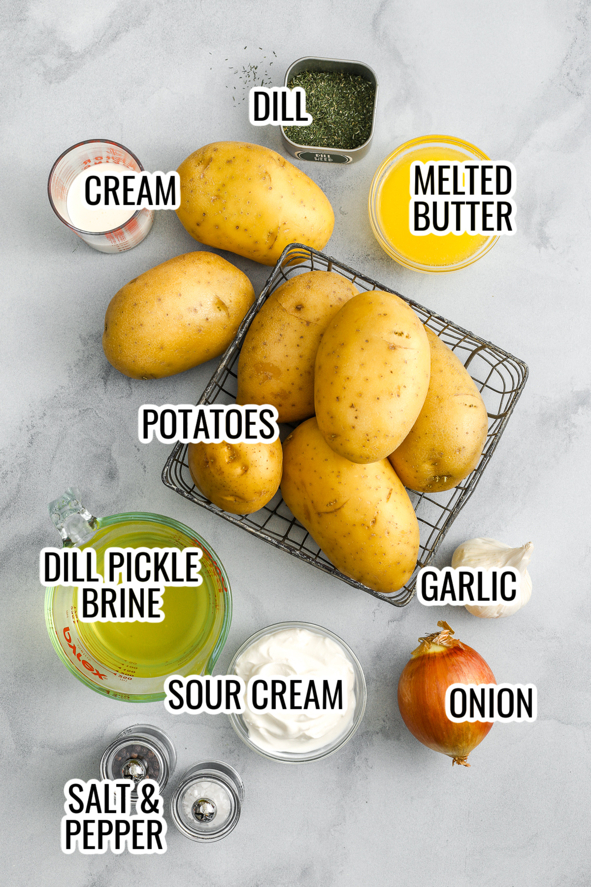 ingredients for dill pickle mashed potatoes including cream, butter, potatoes, including dried dill, dill pickle brine, garlic, onion, butter, cream, sour cream, potatoes, and salt and pepper, with labels
