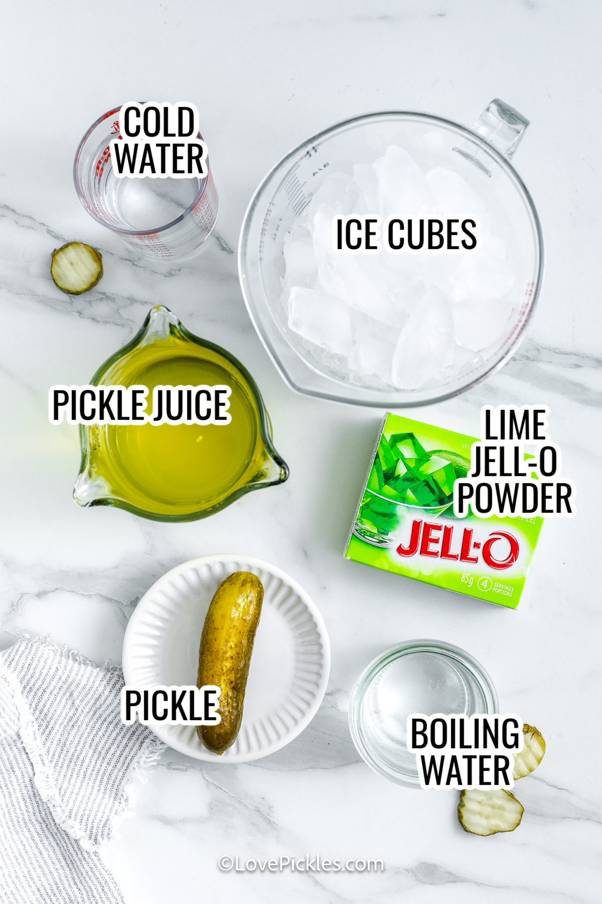 ingedients assembled to make copycat sonic pickle slush, including pickle juice, lime jell-o powder, cold water, pickle, and ice cubes