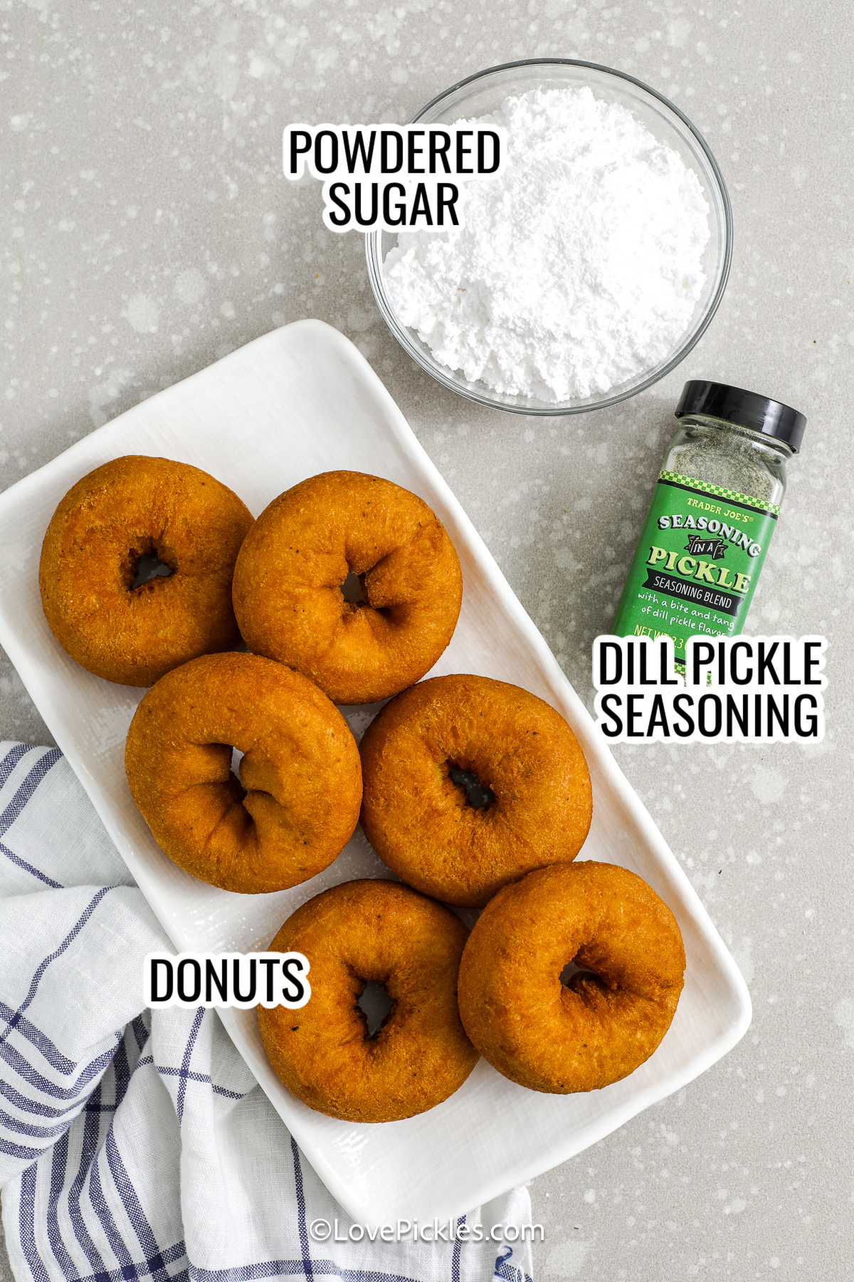 Ingredients to make dill pickle donuts labeled: powdered sugar, dill pickle seasoning, and donuts