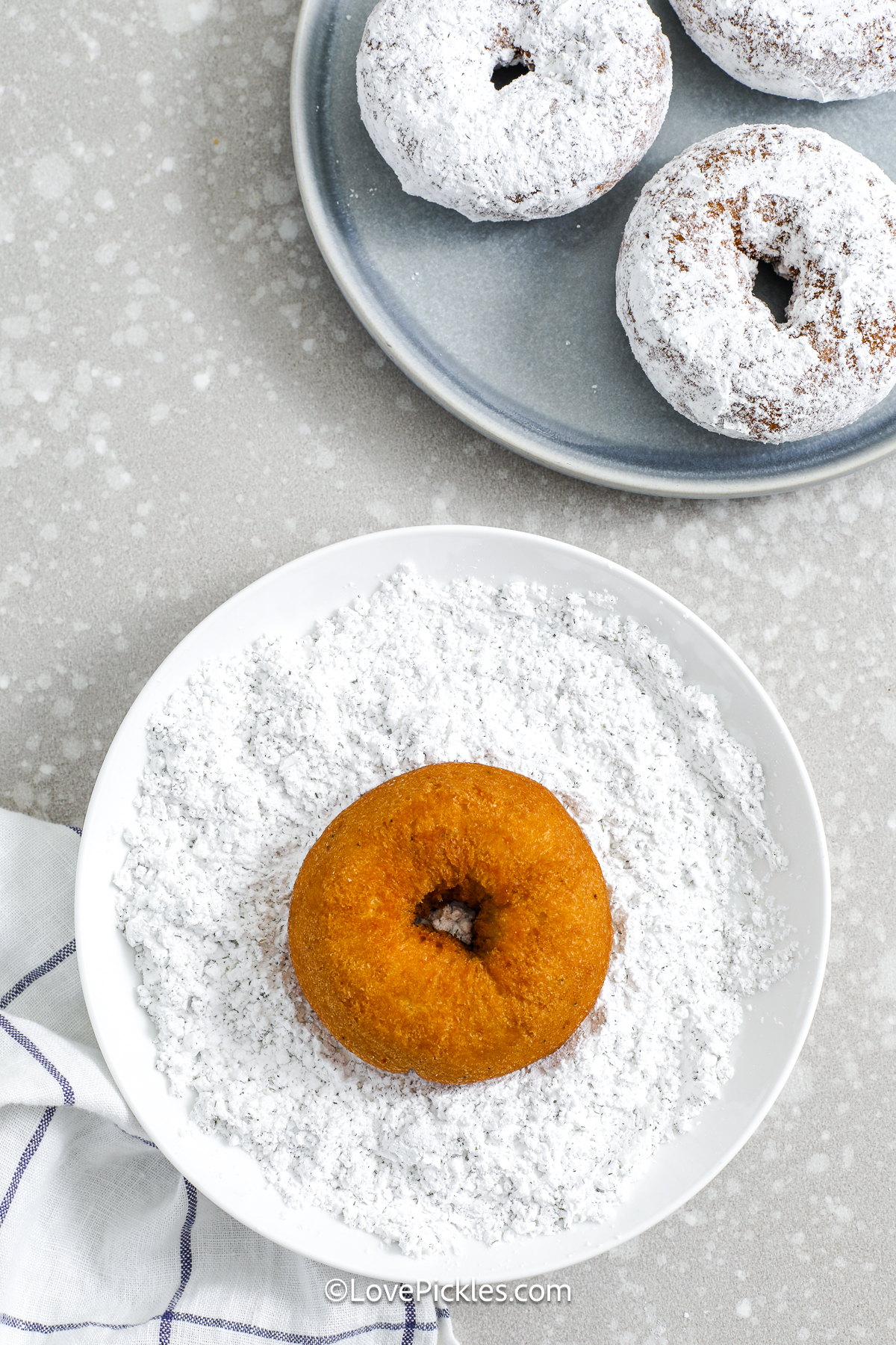 A donut being rolled in dill pickle powdered sugar