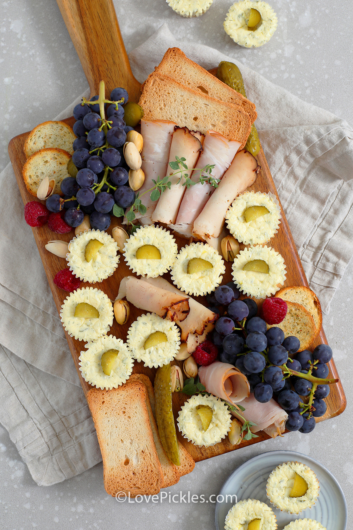 savory dill pickle cheesecake appetizers and other snacks on a board
